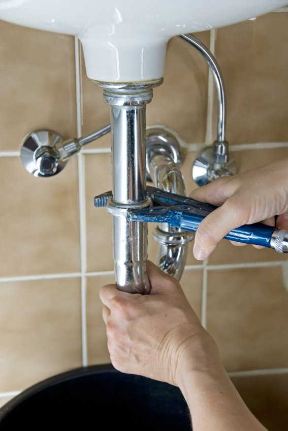 hands of a plumber fixing a leaking tap